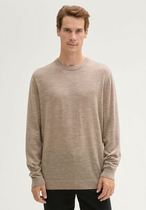 Beżowy sweter z długim rękawem i okrągłym dekoltem, wykonany z miękkiego, teksturowanego materiału. Posiada ściągacze na mankietach oraz luźny krój, minimalistyczny design.