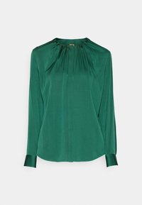 Blouse vert foncé à manches longues avec encolure froncée et poignets boutonnés sur fond blanc.