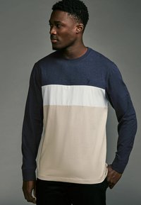 Langermige shirt met een marineblauwe bovenkant, een witte streep in het midden en een beige onderkant. Gemaakt van zachte stof.