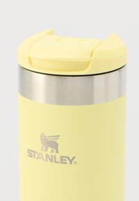 Κίτρινο ταξιδιωτικό κύπελλο από ανοξείδωτο ατσάλι με υφή ματ, ασημί ταινία και ασφαλές καπάκι με αναστροφή. Διαθέτει λογότυπο στο σώμα.