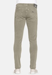 Pantaloni in cotone slim-fit di colore verde oliva con due tasche posteriori, cuciture a vista e una etichetta con marchio sulla vita.