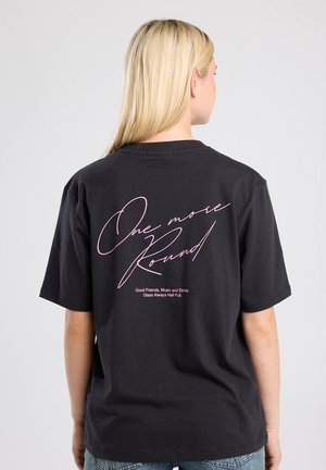 Zwarte katoenen T-shirt met roze cursieve en gedrukte tekst op de achterkant. Relaxed fit met korte mouwen. De tekst bevat "One more Round."