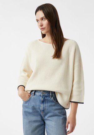 Cremefarbener Rippstrickpullover mit weitem Ausschnitt und Dreiviertelärmeln, kombiniert mit hellblauen Jeans aus Denim, mit geradem Schnitt und vorderen Taschen.