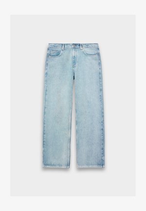 Heledad sinised sirged jalad denim püksid ees taskutega, vöökummiga ja nupuga kinni, ühel lihtsal valgel taustal.