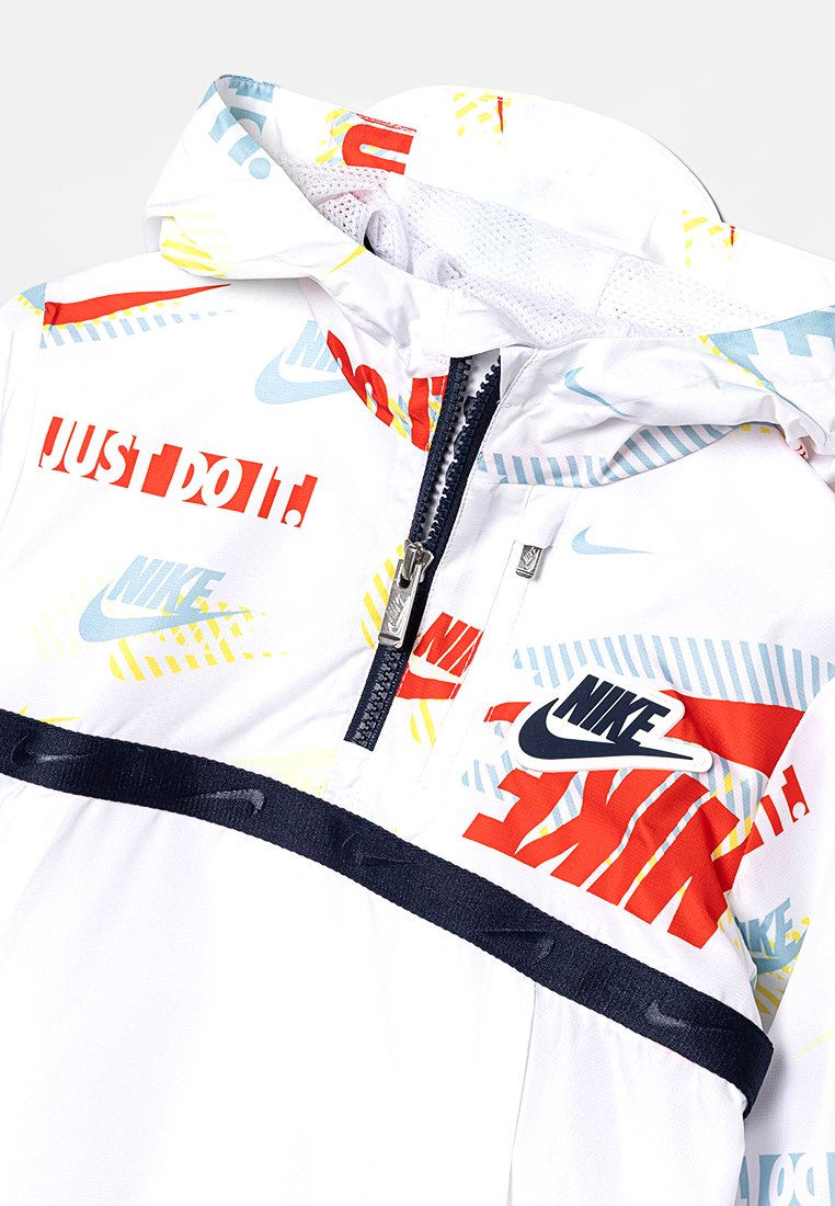Veste Nike blanche avec imprimé graphique en rouge, bleu et jaune. Comprend un col zippé, une poche et un accent noir à l'ourlet. Matériau léger.