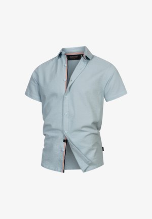 Chemise à manches courtes, de couleur bleu clair, en tissu texturé, avec des finitions orange contrastantes le long du plastron intérieur et un col boutonné.