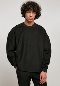 Sort ribbet sweatshirt med lange ærmer, rund hals og afslappet pasform. Stofteksturen er blød med synligt ribmønster.