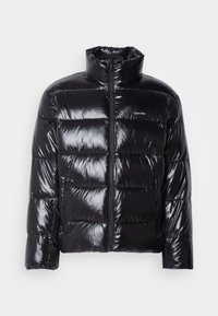 Μαύρο puffer μπουφάν με γυαλιστερή επιφάνεια, διαθέτει ψηλό γιακά, μπροστινό φερμουάρ και δύο πλάγιες τσέπες με φερμουάρ. Σχεδίαση με κουτί και ραβδώσεις.