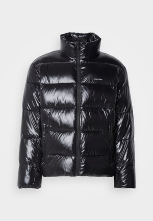 Czarna puchowa kurtka o błyszczącym wykończeniu, z wysokim kołnierzem, zamek błyskawiczny na przodzie oraz dwiema bocznymi kieszeniami na zamek. Projekt w formie pikowania w kwadraty.
