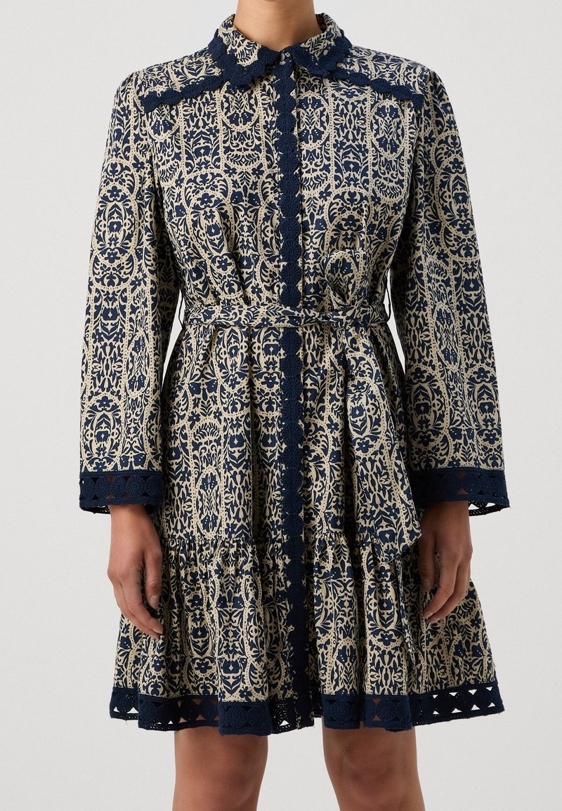 Robe à manches longues avec motif floral bleu marine et beige, bordure en dentelle festonnée au col, devant, aux poignets et à l'ourlet, taille ceinturée, longueur genou.