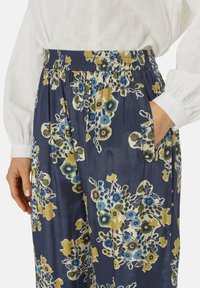 Pantaloni floreali blu navy con cintura elastica, caratterizzati da un mix di fiori blu, gialli e verdi, e tasche laterali per praticità.