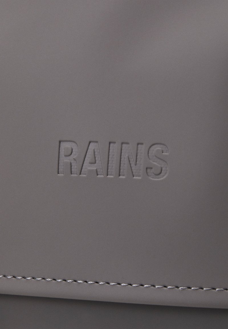 Borsa grigia con logo "RAINS" in rilievo, realizzata in materiale liscio e con cuciture curate. Il design semplice mette in risalto la texture elegante e l'appeal moderno.