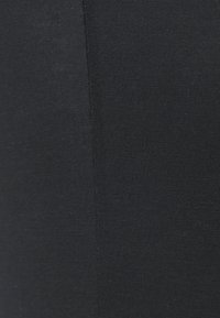 Tejido negro con una textura suave y elástica, con detalles de costura sutiles, que presenta un color uniforme en toda su extensión. Adecuado para capas base.