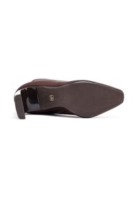 Chaussure en daim marron avec un bout pointu, un talon noir brillant et une semelle en caoutchouc texturée ; design simple avec un minimum de détails sur le talon.