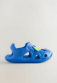 Sandalina in plastica blu con punta chiusa, cinturino regolabile in velcro, fori di ventilazione e accenti colorati sulla parte anteriore.