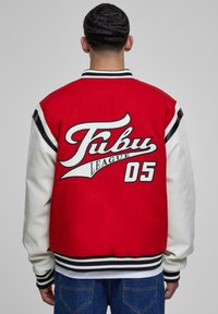 Rød og hvid varsity jakke med sorte striber, der har et stort "Fubu League 05" logo på ryggen og ribbede manchetter.