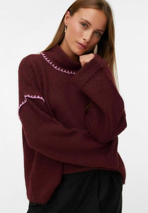 Burgundy knit sweater with a high neckline, long sleeves, and pink stitched accents on the collar and cuffs. Soft, textured fabric.