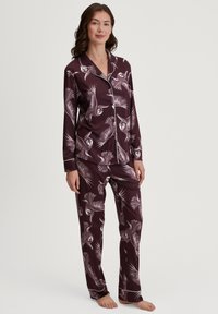 Bordeaux pyjamastel met uilprint. Knop shirt met lange mouwen en een broek, beide met witte bies langs de randen. Glad stoffen textuur.