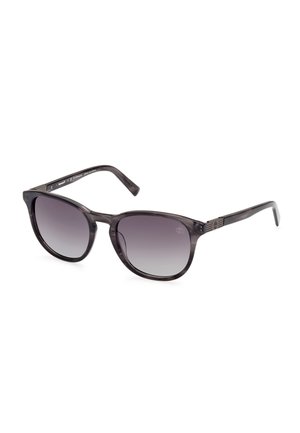 Ochelari de soare rotunzi cu un cadru de culoare neagră gradată. Lentilele sunt întunecate și trec la o nuanță mai deschisă la bază, având detalii subtile pe hardware.