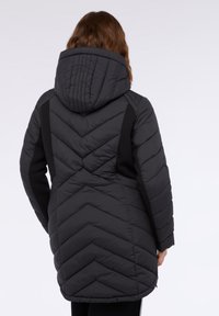 Abrigo tipo puffer negro con patrón de rombos acolchados, capucha desmontable y paneles laterales negros, con cremallera y corte a media longitud.