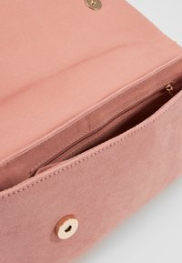 Pink suede clutch purse with gold magnetic snap closure and interior zippered pocket visible inside.