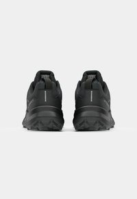 Schwarze Sportschuhe mit einer strukturierten Oberseite, robuster Sohle und reflektierenden Akzenten. Verfügt über einen gepolsterten Kragen und eine verstärkte Ferse für Stabilität.