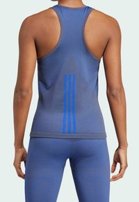 Modrý sportovní nátělník s designem racerback, s třemi svislými modrými pruhy ve středu a hladkou, přiléhavou texturou.