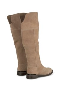 Bottes en daim beige jusqu'au genou avec une texture lisse, un haut arrondi et un petit talon empilé. Détail de couture distinctif et panneau arrière renforcé.