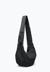 Musta pehmeä kangaskangaskassi, jossa leveä olkahihna ja sivuvetoketjutasku, esitetty valkoista taustaa vasten.