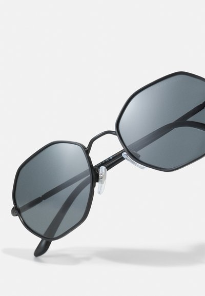 Black octagonal sunglasses with dark lenses, thin metal frame, and clear nose pads. Features a minimalist design and sleek finish.