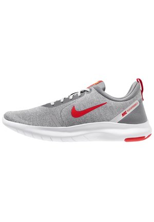 Grijze Nike Flex Experience 8 sneaker met rode swoosh, witte zool, grijze veters en rode accenten op hiel en tong, getoond in zijaanzicht.