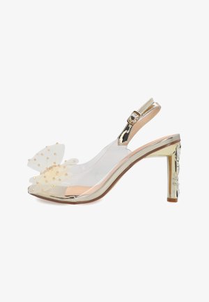 Højhælet slingback-sko med klare sider, guldfarvet metallic hæl og kant samt en dekorativ let sløjfe med guldperler på tåen.