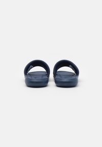 Tengerészeti kék slip-on szandálok texturált talppal és nyitott hátsó kialakítással. Rugalmas anyagból készült, széles pántokkal a kényelem érdekében.