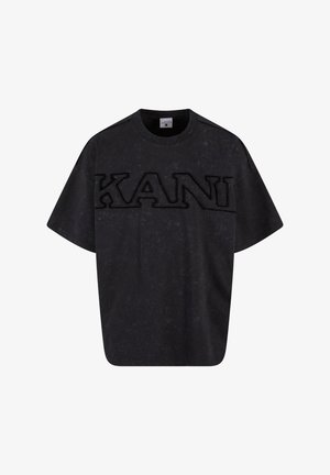 T-shirt noir oversize avec un logo "KANI" texturé au centre. Fabriqué en tissu doux, il a un col rond et des manches courtes.