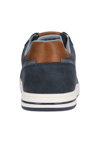 Laivasilmä kengät, joissa on ruskea nahkakoriste kantapäässä, teksturoitu tekstiilipinta, valkoinen kumipohja, ja nauhattoman muotoilun ansiosta helppo pukea.