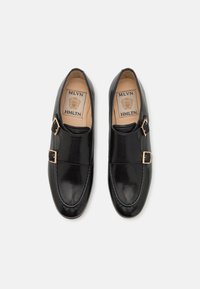 Svarta läderskor med en slät yta, med en dubbelspänne-accent och en rundad tåt design. Inuti finns en beige innersula med logotyp.