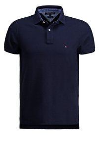 Polo bleu marine en coton, avec un col à deux boutons, des manches courtes et un petit logo sur la poitrine. Texture lisse.