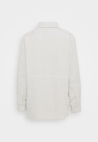 Light beige corduroy long-sleeve shirt with collar, buttoned cuffs, and subtle vertical stripes, shown from the back.