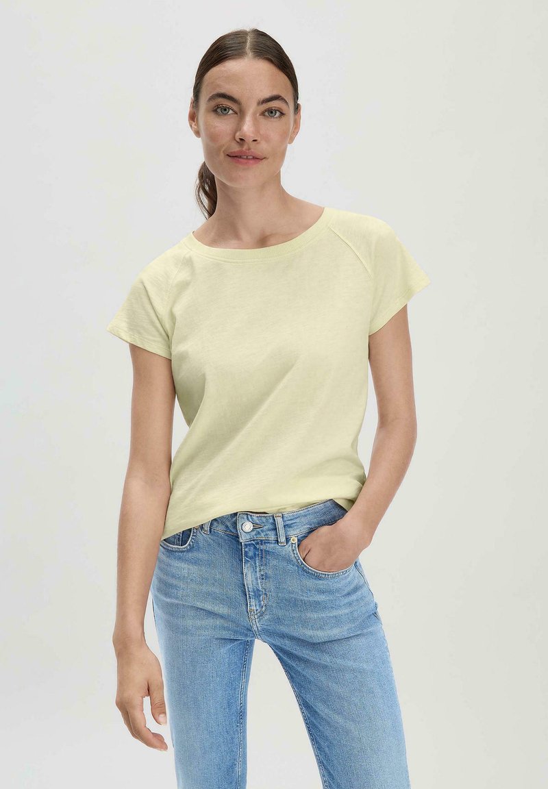 Lichtgele katoenen t-shirt met korte mouwen en een brede halslijn, gecombineerd met lichtblauwe denim spijkerbroek. Eenvoudig ontwerp, casual pasvorm.