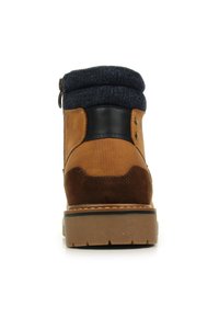 Bota de tobillo de cuero marrón con un puño de denim, paneles texturizados, acentos negros suaves y una suela de goma duradera. Cuenta con una cremallera lateral y herrajes metálicos.