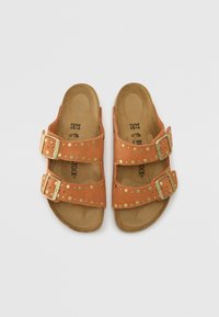 Sandales en suède beige avec deux sangles réglables, quincaillerie couleur or et clous décoratifs. Semelle intérieure douce et rembourrée pour le confort. Taille 37.