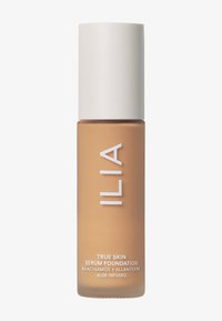 ILIA True Skin Serum Foundation i en matt, brun flaske. Har en rund, hvit kapsel. Tekst i hvitt inkluderer produktnavn og ingredienser.