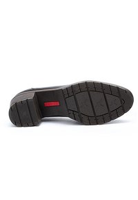 Suola di scarpa in gomma nera con battistrada a motivi e un'etichetta rossa. Presenta una punta arrotondata e un'altezza del tacco modesta per una maggiore aderenza.