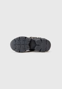 Zwarte rubberen schoenenonderzijde met een gestructureerd patroon van cirkelvormige en ovale vormen, ontworpen voor grip en stabiliteit.