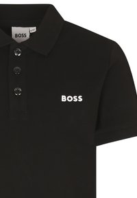 Black polo shirt made of textured fabric. Features a classic collar, three-button placket, and white "BOSS" logo on the chest.