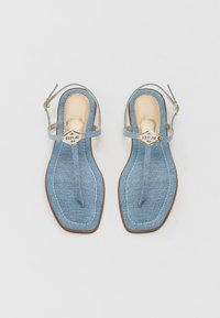 Sandale slingback din denim cu o talpă interioară bej, vârf ascuțit și accente din metal aurit. Prezintă cusături albe și o talpă plată.