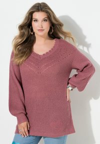 Sweter dziany w kolorze pudrowego różu z ozdobnym dekoltem w kształcie litery V i wzorem diamentowym. Posiada długie rękawy i luźny krój.