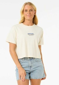 Krótkie jasne t-shirt z mieszanki bawełny, z niebieskim logo na piersi, zestawione z jasnoniebieskimi dżinsowymi szortami.