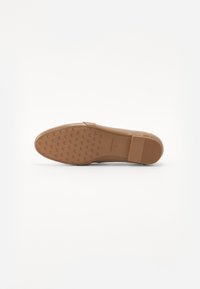 Semelle de chaussure synthétique beige avec motif de grip. Dotée d'un talon rectangulaire et d'un design minimaliste. Plate avec une finition lisse.
