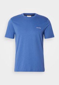 Blue cotton t-shirt with a crew neck, short sleeves, and a minimalist white "Calvin Klein" logo on the left chest. Plain design.